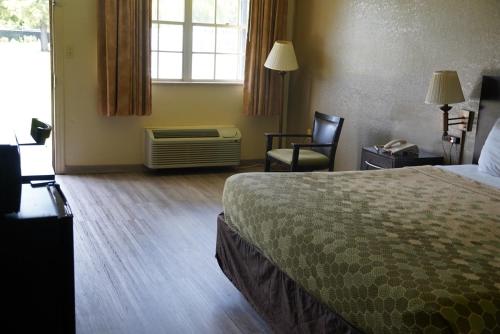 a hotel room with a bed and a chair and a window at Econo Lodge Jacksonville South in Jacksonville