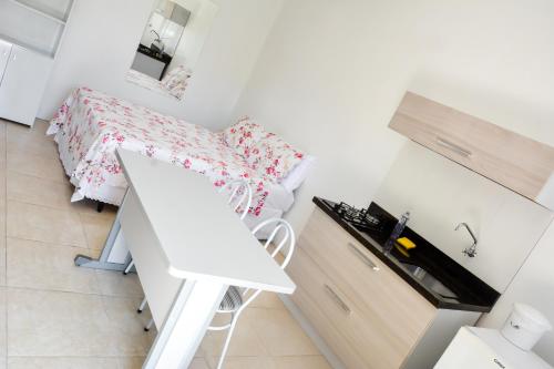 a small white bedroom with a bed and a desk at Classe aluguéis apts in Imbé