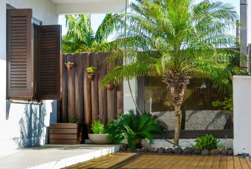 a courtyard with palm trees and a fence at Classe aluguéis apts in Imbé