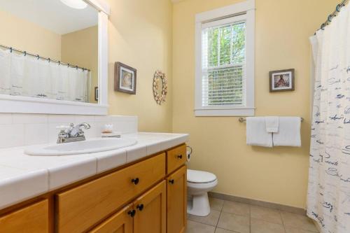 ein Bad mit einem Waschbecken, einem WC und einem Fenster in der Unterkunft Starfish Cottage in Lincoln City