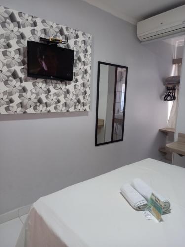 a room with a tv on a wall with a bed at Hotel Mandino in Alta Floresta