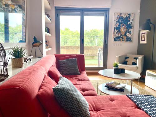Apartamento El Robledal في Cirueña: غرفة معيشة مع أريكة حمراء وطاولة