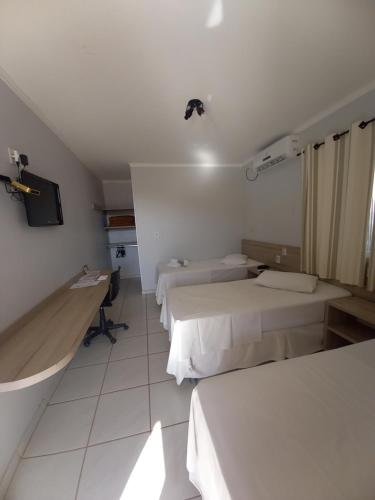a hotel room with two beds and a tv at Hotel Mandino in Alta Floresta