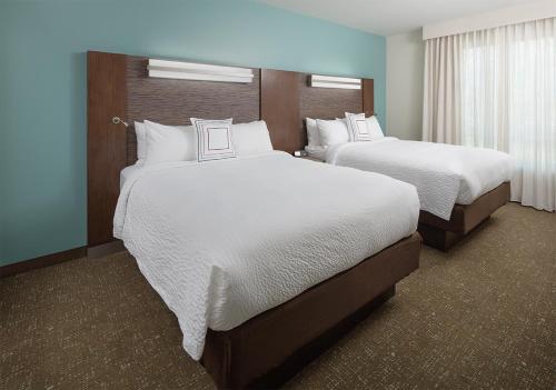 a hotel room with two beds with white sheets at Residence Inn by Marriott Ontario Rancho Cucamonga in Rancho Cucamonga