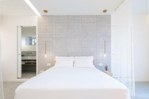 a bedroom with a white bed and a tiled wall at Terra del Sasso Suites - Design Architetto Salvatore Spataro in Sasso di Castalda