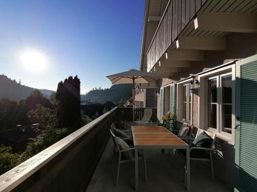 a balcony with a wooden table and chairs on it at WÄLDER: Quartier Haus im Glück in St. Blasien