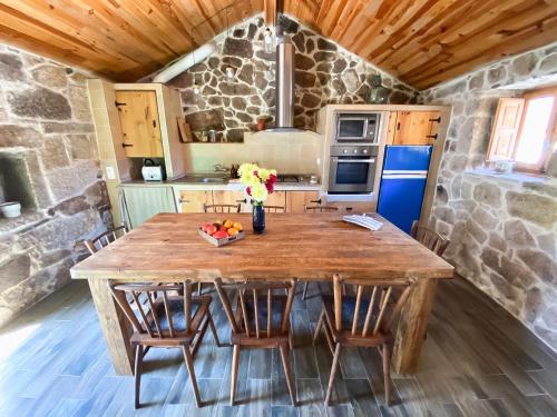 una mesa de madera en una cocina con una pared de piedra en Casa rural familiar con vistas al rio en Galicia, en Puentesampayo