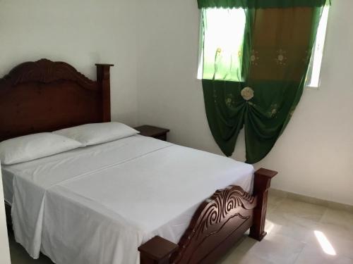 a bedroom with a bed and a window with green curtains at Aparta hotel El Sol, Home near AirPort SDQ in Boca Chica