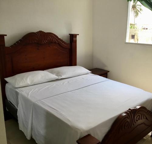 a bedroom with a large bed with white sheets at Aparta hotel El Sol, Home near AirPort SDQ in Boca Chica