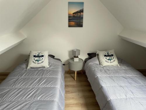 ein Schlafzimmer mit 2 Betten und einem Tisch mit einem Bild in der Unterkunft L'ESCALE in Le Portel