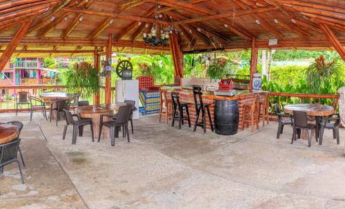 eine Terrasse mit Tischen und Stühlen sowie eine Bar in der Unterkunft Finca Hotel El Tizon in Quimbaya
