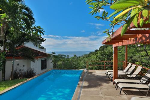 a pool with chairs and the ocean in the background at Casa Frangipani in Montezuma