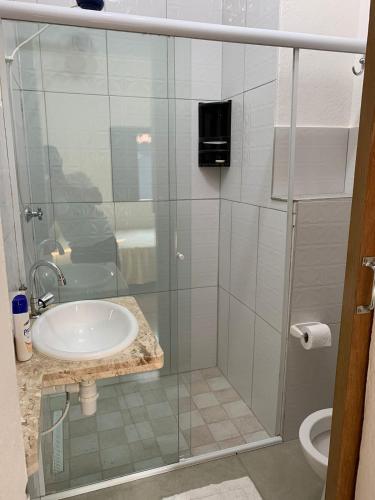 a bathroom with a glass shower with a sink at arco iris in Camburi