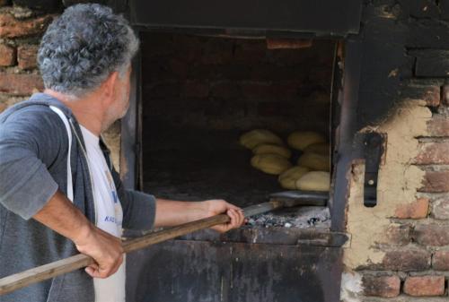 a man putting food into a brick oven at Šurička bajka in Loznica