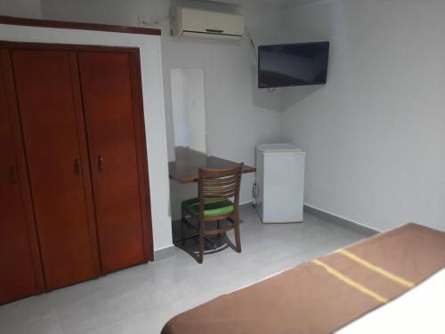 a room with a table and a chair and a television at PEDRA BONITA PRECIOSO HOTEL ltda in Itaboraí