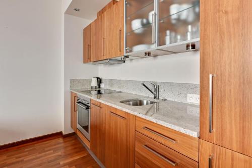 a kitchen with wooden cabinets and a sink at Grand Apartments - Willa Morska Premium in Sopot