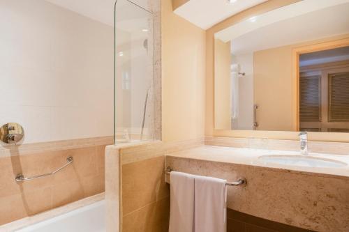 a bathroom with a tub and a sink and a mirror at Iberostar Waves Rose Hall Beach - All Inclusive in Montego Bay