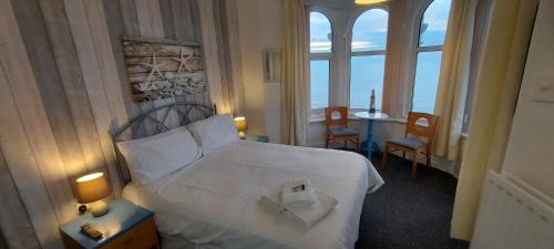 ブラックプールにあるBowies Lodgeのベッド、テーブル、窓が備わるホテルルームです。