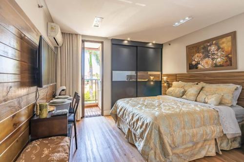 a bedroom with a bed and a desk and a television at Flat no Life com espetacular vista do lago in Brasilia