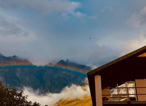 a rainbow in the mountains with a building at Cottage Kesane in Stepantsminda