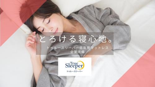 a woman sleeping on a bed with a sign at Swanky Hotel Otomo in Sapporo