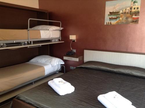 two beds in a hotel room with white towels at Villa Le Logge in Ventimiglia