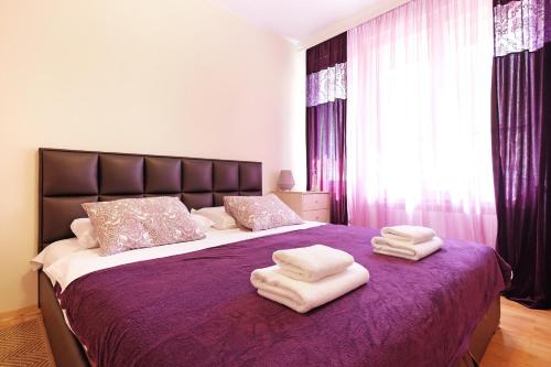 Un dormitorio con una cama morada con toallas. en Paradise Starry Suite-City center Belgrade en Belgrado