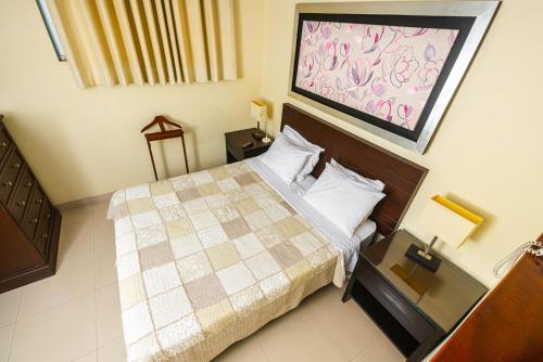 a small bedroom with a bed with a checkered blanket at Posada Blanca Hotel Boutique in Piura