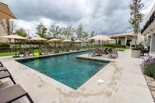 a swimming pool with chairs and umbrellas at Hermoso depto con alberca en el condo La Luminaria Casonas y Villas in San Miguel de Allende