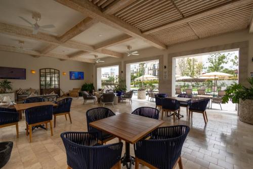 a restaurant with tables and chairs and windows at Hermoso depto con alberca en el condo La Luminaria Casonas y Villas in San Miguel de Allende