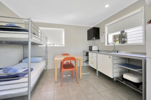 a kitchen with bunk beds and a table and a sink at Cane Village Holiday Park in Bundaberg