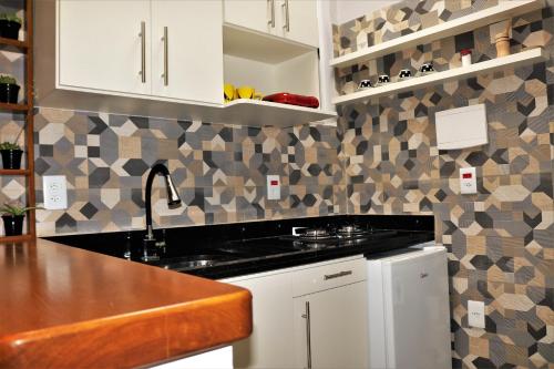a kitchen with white cabinets and a black counter top at Aconchegante apartamento Teresópolis in Teresópolis