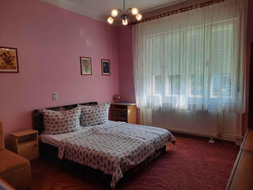 een slaapkamer met roze muren, een bed en een raam bij Apartments in Siofok - Balaton 41945 in Siófok