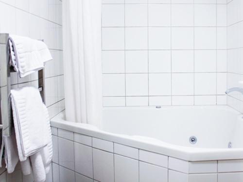 a white bathroom with a tub and a sink at Harbour View Motel in Timaru