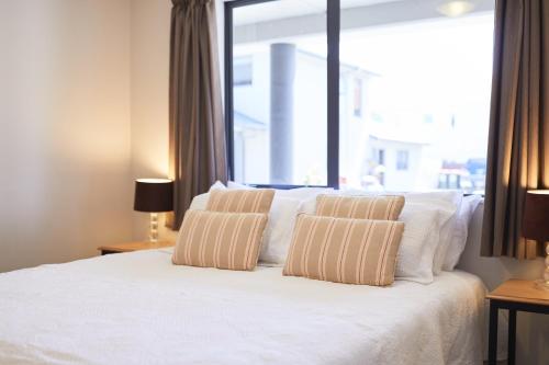 a bedroom with a bed with two pillows and a window at Blenheim Palms Motel in Blenheim