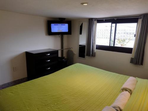 a bedroom with a green bed and a television at Mi Depa Vainilla en pleno Centro de la Ciudad in Ciudad Valles