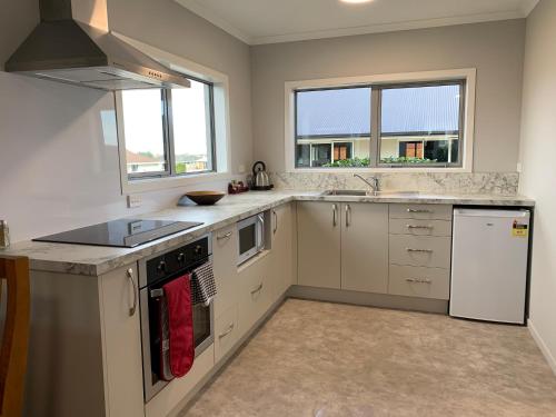 a kitchen with white appliances and two windows at Kingswood Motel in Waimate