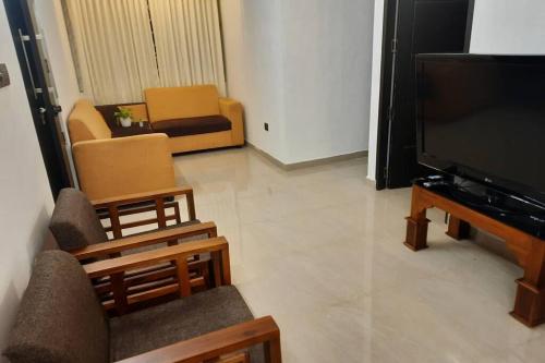 a living room with a flat screen tv and chairs at BMRAN Apartment A in Ernakulam