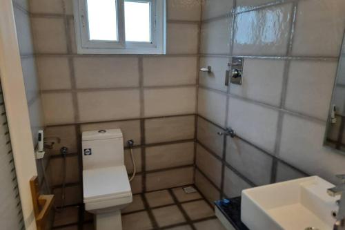 baño con aseo y lavabo y ventana en BMRAN Apartment A en Ernakulam