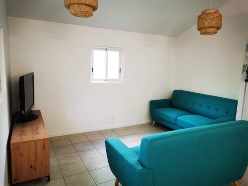 a living room with a blue couch and a tv at Case Lénaron in Saint-Joseph