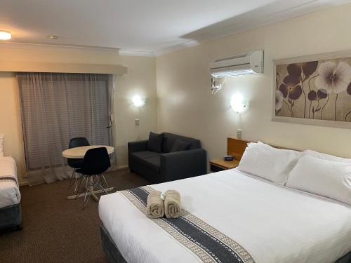 a hotel room with a bed and a chair at All Settlers Motor Inn Parkes in Parkes