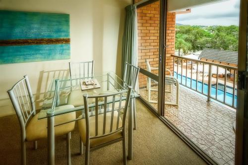 a dining room with a table and chairs and a balcony at Sandcastles Holiday Apartments in Coffs Harbour