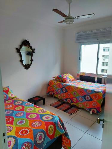a bedroom with two beds and a ceiling fan at Apto pé na areia Praia das Pitangueiras - Centro in Guarujá
