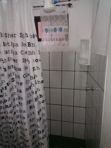 a bathroom with a shower curtain with writing on it at Canto do Riacho Chales in Trindade