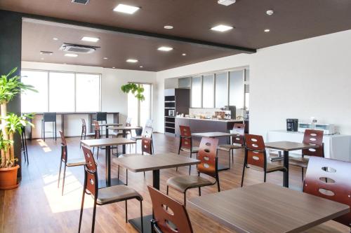 a restaurant with tables and chairs and a kitchen at Hotel chez toi Kanonji in Kanonji