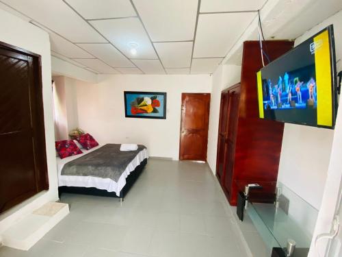 een slaapkamer met een bed en een flatscreen-tv bij LA Perla Sabanera CTG in Cartagena