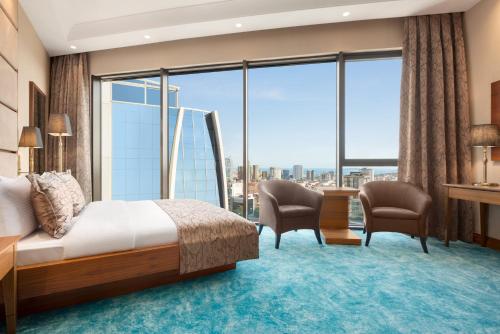 a hotel room with a bed and chairs and a large window at Days Hotel by Wyndham Istanbul Maltepe in Istanbul