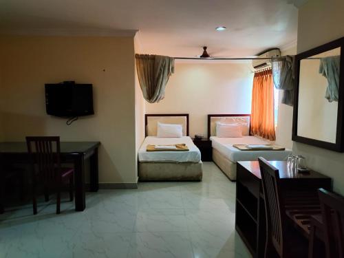 1 dormitorio con 2 camas, escritorio y TV en Hotel Geetha International, en Thoothukudi