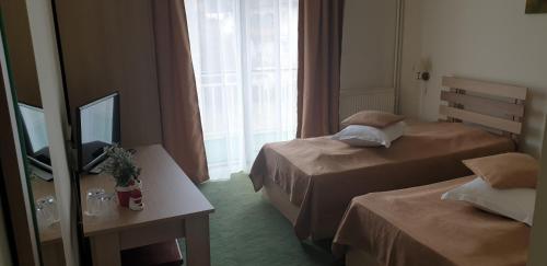 ein Hotelzimmer mit 2 Betten und einem TV in der Unterkunft Pensiunea Confort in Buşteni