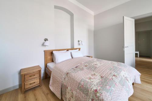 a white bedroom with a bed and a night stand at Lovely, Best View Apartment, Vilnius City Centre in Vilnius